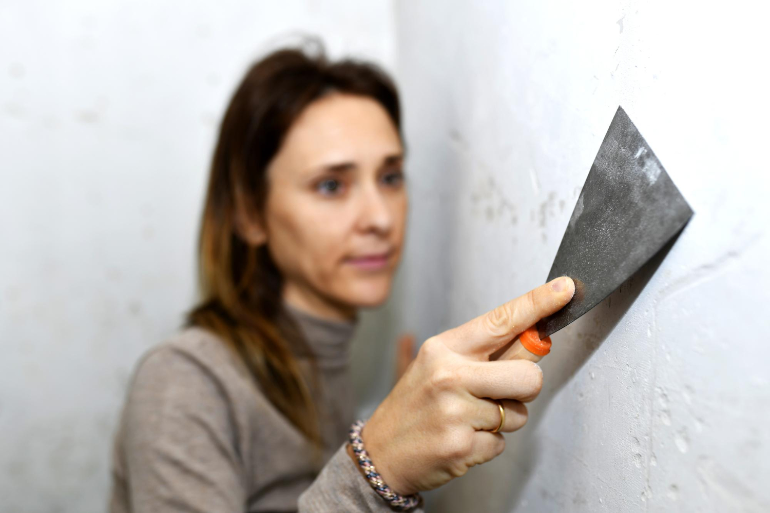 Mulher coloca massa para infiltração de parede