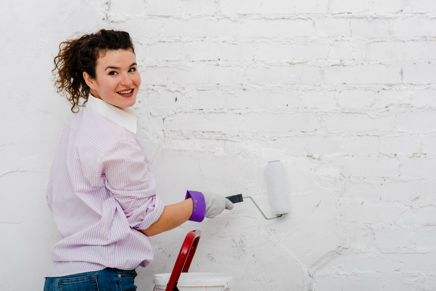 Mulher usando tinta para infiltração de parede interna