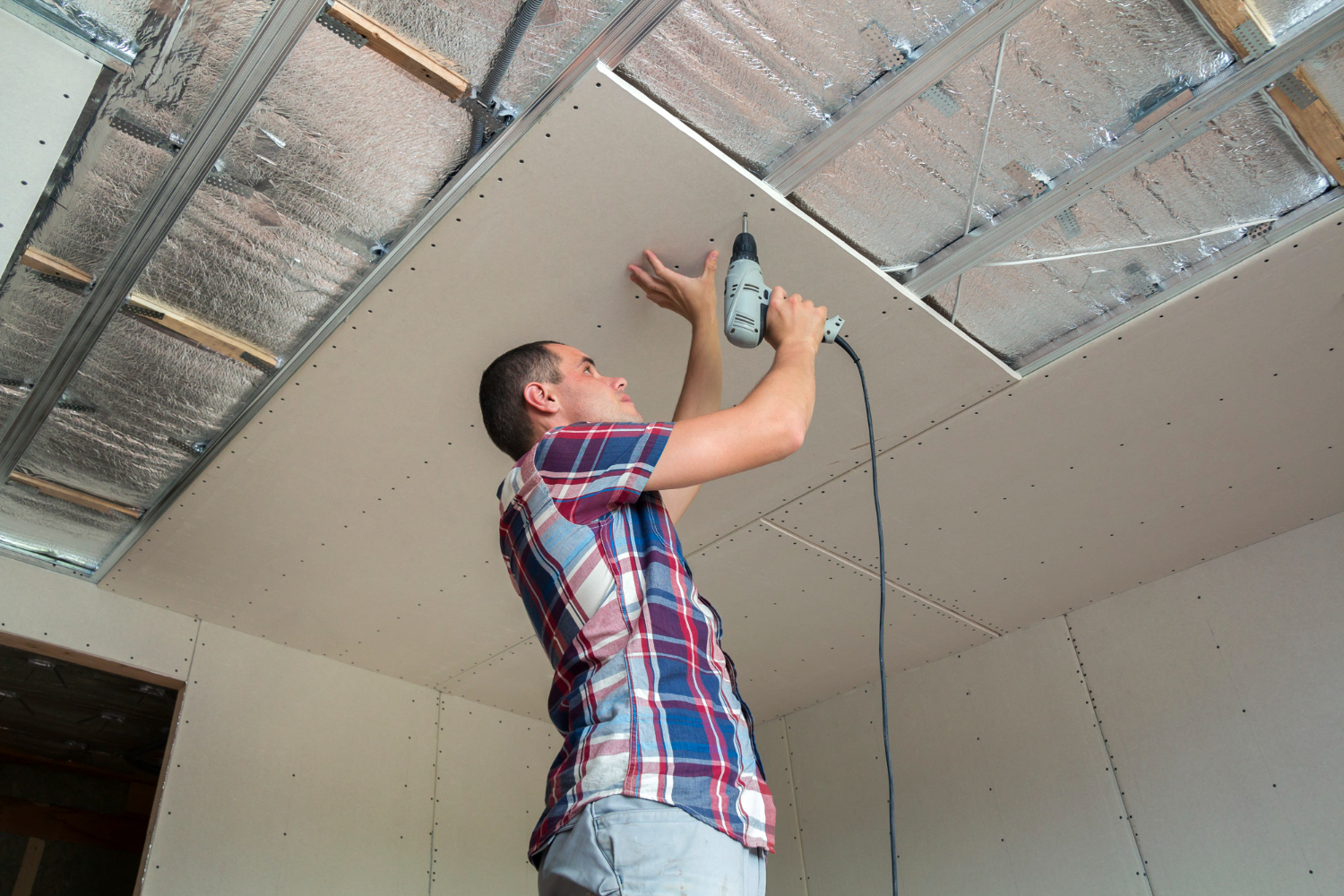 Profissional durante instalação de parte do forro de uma casa